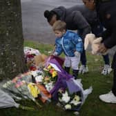 Flowers are left near the scene after three young boys died when a number of children fell through ice on a lake in Solihull. 