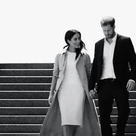 A black and white image of Meghan Markle and Prince Harry walking down a flight of stairs together, hand in hand and smiling (Credit: Netflix) 