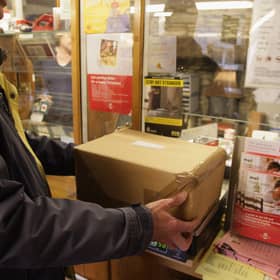 Customers weigh packages at the post office.