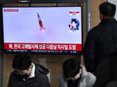 A man watches a television screen showing a news broadcast with file footage of a North Korean missile test, at a railway station in Seoul on December 31, 2022