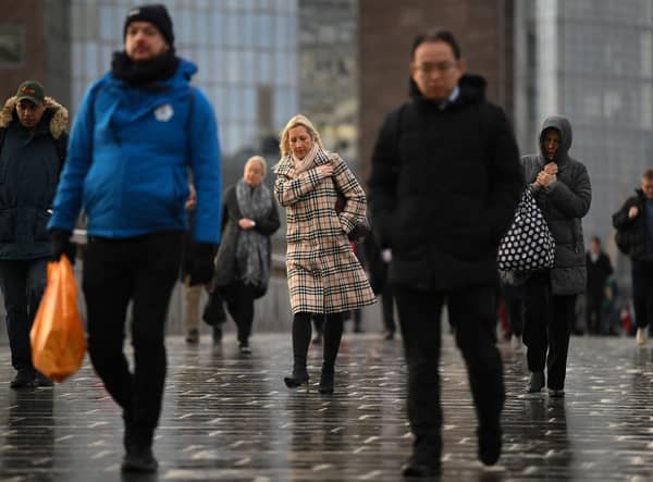 Commuters on their way to work cross London Bridge in central London.