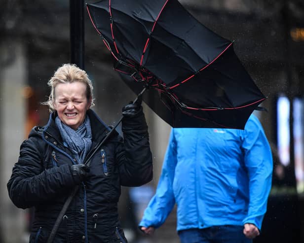 A woman battles to keep control of her umbrella as she walks through a rain shower in Glasgow.