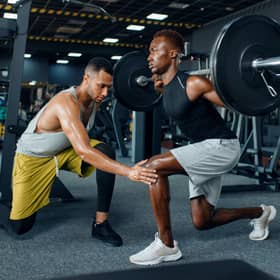 Man with his trainer in gym (Adobe)