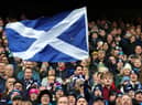A Scotland fan waves a national flag as they enjoy the pre-match atmosphere prior to a Six Nations Rugby match at Murrayfield Stadium