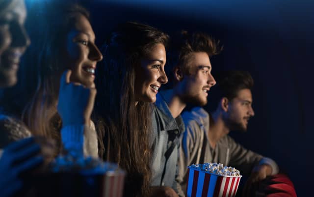 An audience of cinema goers enjoying popcorn - can you guess which of them is called Elizabeth? (Credit: Adobe)