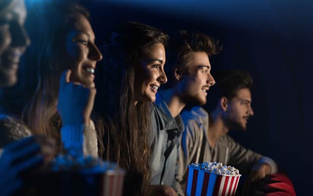 An audience of cinema goers enjoying popcorn - can you guess which of them is called Elizabeth? (Credit: Adobe)