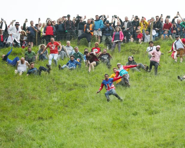 Contestants in the men’s downhill race chase the cheese down the hill in June 2022 in Gloucester, England. 