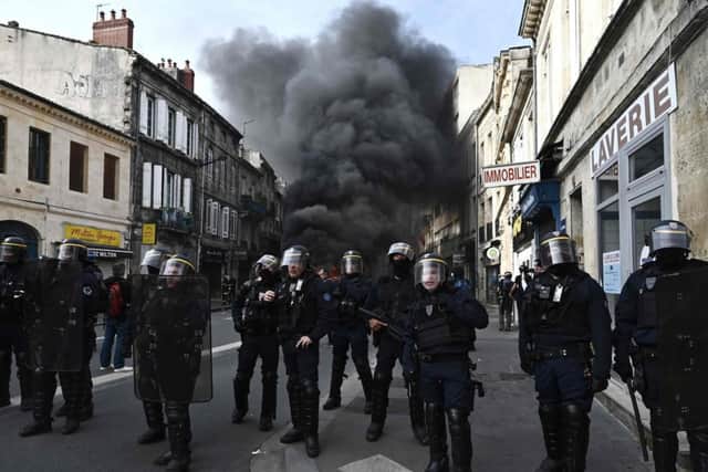 French French Republican Security Corps (CRS - Compagnies Republicaines de Securite) police officers in riot gear operate during a demonstration, with a smoke rising in the background, a week after the government pushed a pensions reform through parliament without a vote, using the article 49.3 of the constitution. (Photo by PHILIPPE LOPEZ/AFP via Getty Images)