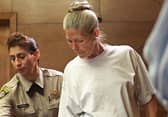 Corrections officer Sandra Fuentes (L) assists inmate Leslie Van Houten (R) as arrives for her parole hearing before members of the Board of Prison Terms 28 June 2002 at the California Institution for Women in Corona, California.