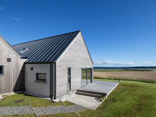 The longhouse is positioned low on a hillside, just above a sandy beach on the coast of the stunning island of Lewis.