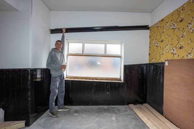 Carl Falconer standing next to the shelf where pool balls roll up instead of down.