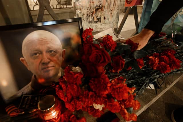 A man lays flowers at a makeshift memorial in honour of Yevgeny Prigozhin.