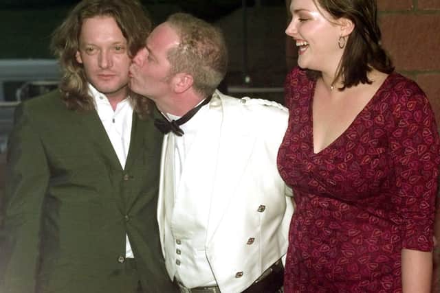Film director Peter Mullan (centre) jokingly gives leading actor Douglas Henshall (L) a kiss, as model Sophie Dahl looks on at the UK premiere of his film 'Orphans' in Glasgow. (1999) 