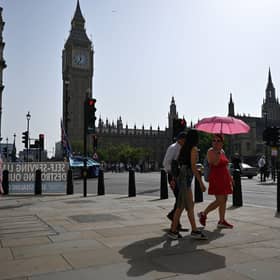 Pedestrians walk in the midday sun past the Palace of Westminster in central London on September 6, 2023 as the late summer heatwave continues.