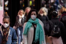 A woman wears a face mask while walking on Oxford Street.