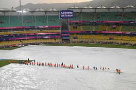 Members of the ground staff cover the field as rain delays the warm-up match between Bangladesh and England ahead of the ICC men's cricket World Cup, at the Assam Cricket Association Stadium in Guwahati on October 2, 2023. (Photo by Biju BORO / AFP) (Photo by BIJU BORO/AFP via Getty Images)