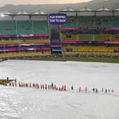 Members of the ground staff cover the field as rain delays the warm-up match between Bangladesh and England ahead of the ICC men's cricket World Cup, at the Assam Cricket Association Stadium in Guwahati on October 2, 2023. (Photo by Biju BORO / AFP) (Photo by BIJU BORO/AFP via Getty Images)