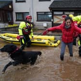 A member of the emergency services helps resident Laura Demontis from a house in Brechin, Scotland, as Storm Babet batters the country.