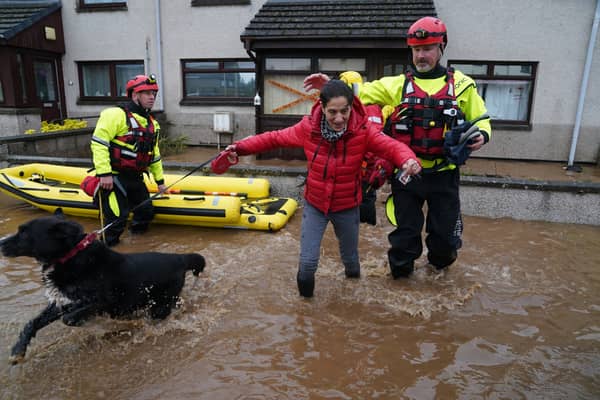 A member of the emergency services helps resident Laura Demontis from a house in Brechin, Scotland, as Storm Babet batters the country.