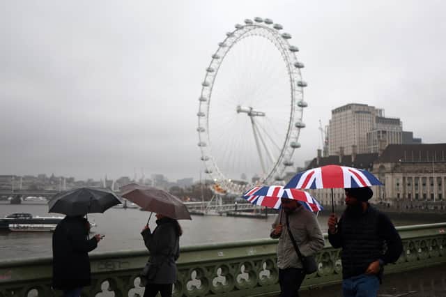 Pedestrians holding Union Jack umbrellas walk in the rain past the London Eye in central London on December 19, 2023. 