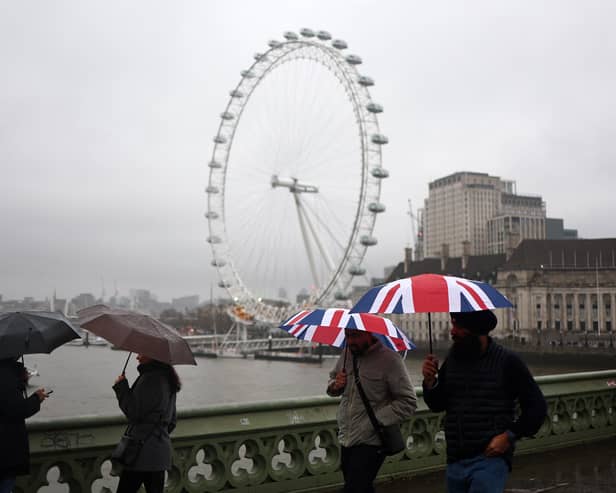 Pedestrians holding Union Jack umbrellas walk in the rain past the London Eye in central London on December 19, 2023. 