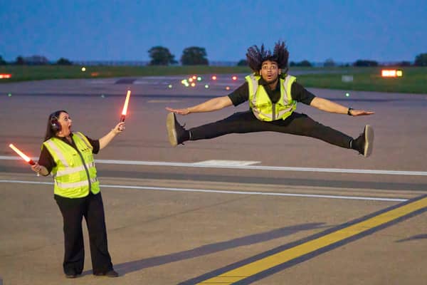 Airport ground handlers perform lively dance routine on runway.