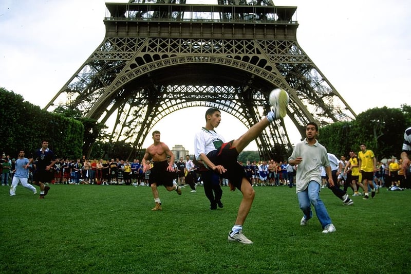 Scotland fans enjoy a game of football with locals underneath the Eiffel Tower.