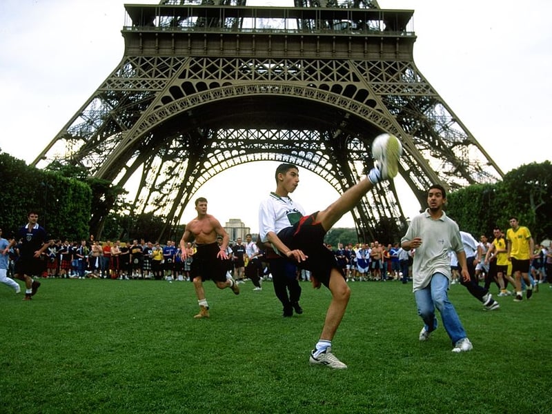 Scotland fans enjoy a game of football with locals underneath the Eiffel Tower.