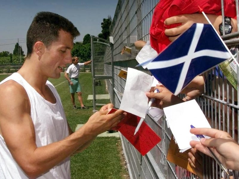 John Collins signs autographs for fans waiting at the Scotland training base in France.