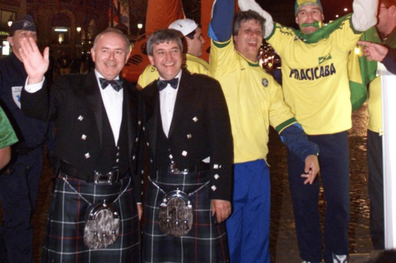 Scottish and Brazilian fans stand in front of a 20-meter high giant being driven down the Champs-Elysees avenue.