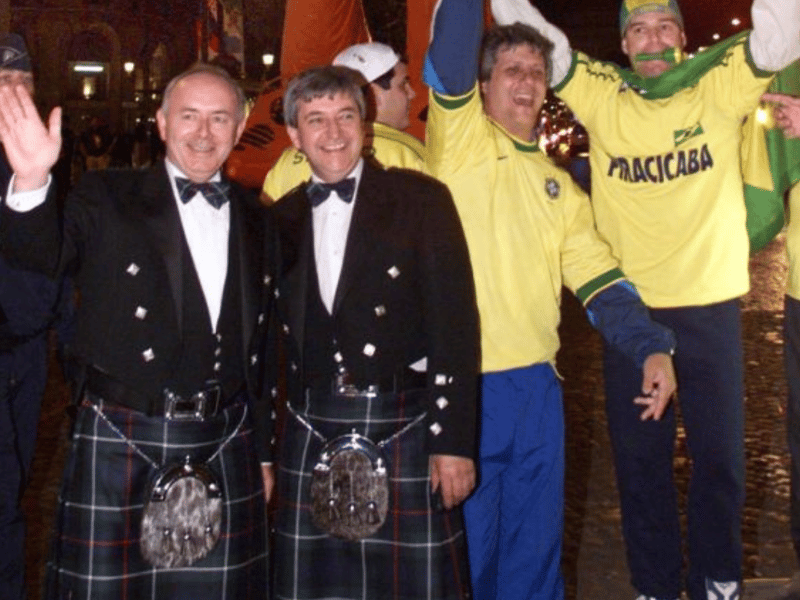Scottish and Brazilian fans stand in front of a 20-meter high giant being driven down the Champs-Elysees avenue.