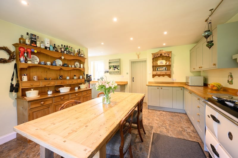 The house has a dining room, sitting room, dining kitchen, sun room and utility, three bedrooms, a shower room and a bathroom. Outside are landscaped gardens with pathways and planting, vegetable raised beds, a polytunnel and greenhouse, plus outbuildings. 