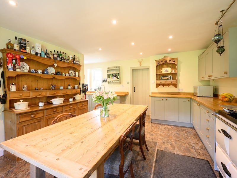 The house has a dining room, sitting room, dining kitchen, sun room and utility, three bedrooms, a shower room and a bathroom. Outside are landscaped gardens with pathways and planting, vegetable raised beds, a polytunnel and greenhouse, plus outbuildings.