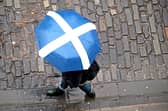 A member of the public with a Saltire umbrella walks along Victoria Street in Edinburgh. Picture: PA