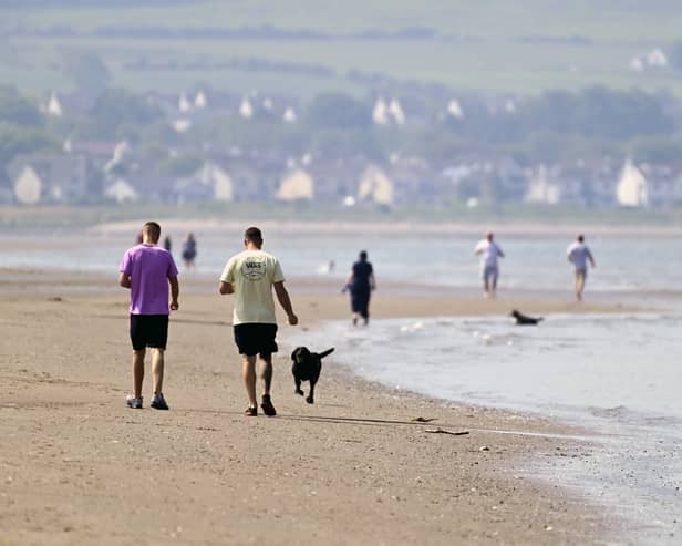 People stroll along Ayr Beach, amid a warmer spell of weather in Scotland. Picture: John Devlin