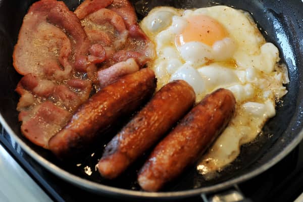 Egg, sausages and bacon being fried in a frying pan
