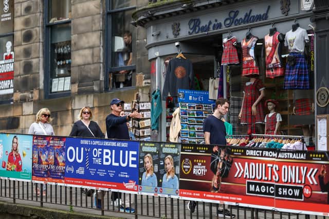 Members of the public walk past posters advertising shows ahead of the Edinburgh Festival Fringe.