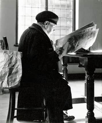 Woman with a newspaper in the Ward Rd Reading Room, 1960s.