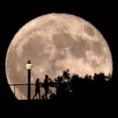 People walk in front of a rising supermoon at Griffith Observatory in Los Angeles