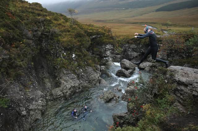 A scuba diver jumps from a rock ledge into one of the Fairy Pools.