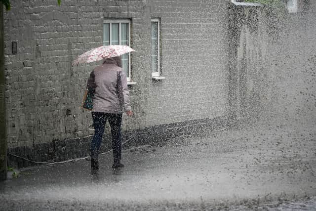 A pedestrian negotiates a partially flooded footpath as heavy rain starts. Picture: Christopher Furlong/Getty Images