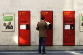 A man puts a letter get into a postbox at a Post Office. Picture: Adrian Dennis/AFP via Getty Images