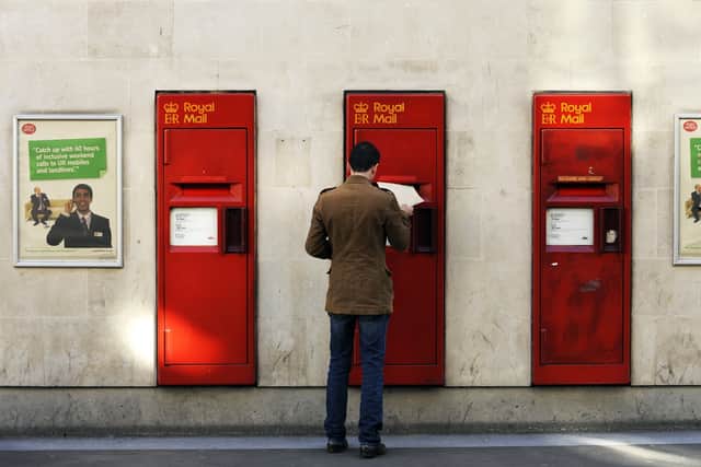 A man puts a letter get into a postbox at a Post Office. Picture: Adrian Dennis/AFP via Getty Images