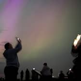 People take out their phones to try and capture the Northern Lights on camera.