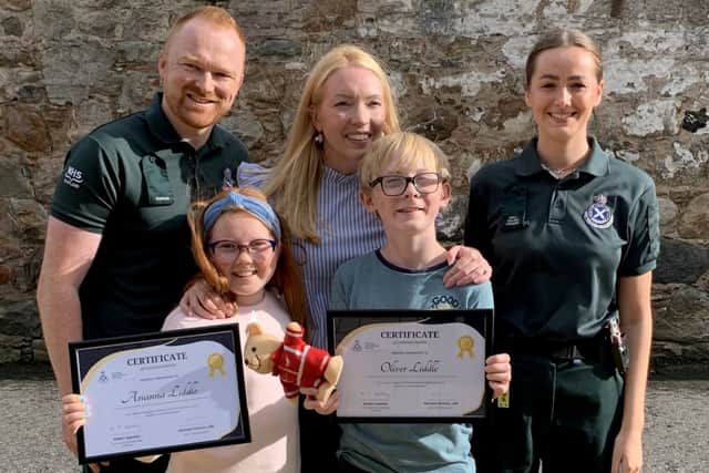 Arianna Liddle (centre), her brother Oliver (centre right) and their mother, Donna (second right), with Scottish Ambulance Service staff. Picture: Scottish Ambulance Service/SWNS