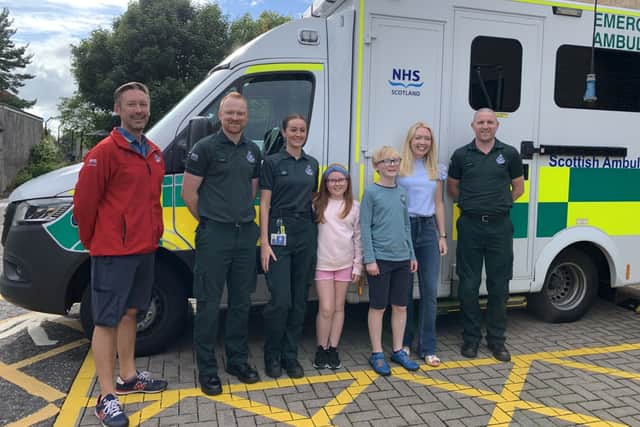 Arianna Liddle (centre), her brother Oliver (centre right) and their mother, Donna (second right), with Scottish Ambulance Service staff. Picture: Scottish Ambulance Service/SWNS