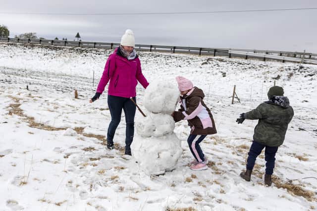 Nathalie, Haylie and Lewellyn Smith build a snowman on a snow covered sports field in Warden, Free State province, South Africa, on September 21, 2024.