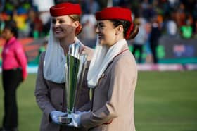 Emirates Airlines staff members hold the ICC women's T20 World Cup trophy.