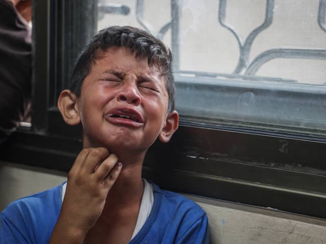 A Palestinian boy mourns relatives killed in Israeli missile strikes in the central Gaza Strip last month (Picture: Eyad Baba)