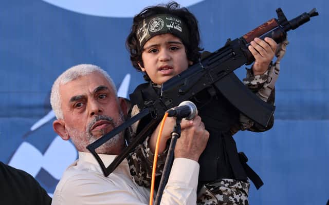 Former Hamas leader Yahya Sinwar, who was killed earlier this month by the IDF, holds a child with a Kalashnikov rifle during a rally in Gaza City in 2021